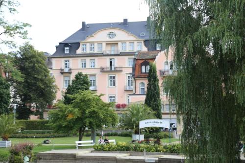un grand bâtiment rose avec un panneau devant lui dans l'établissement Villa Thea Hotel am Rosengarten, à Bad Kissingen