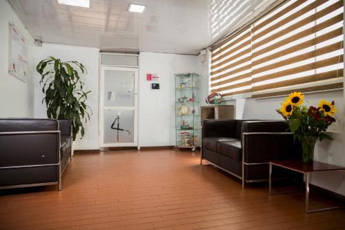a waiting room with two couches and a table with flowers at Deportel Bogotá in Bogotá