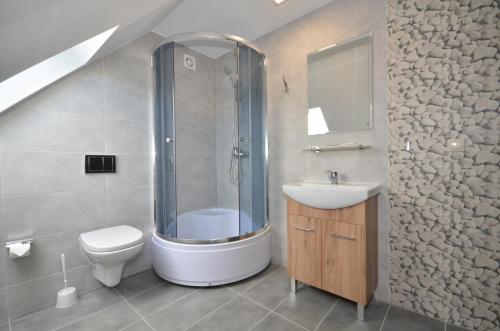 a bathroom with a shower and a toilet and a sink at Pod Strzechą in Darłowo