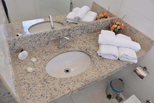 a bathroom counter with a sink and towels on it at Gran Norte Hotel - Salinas - MG in Salinas