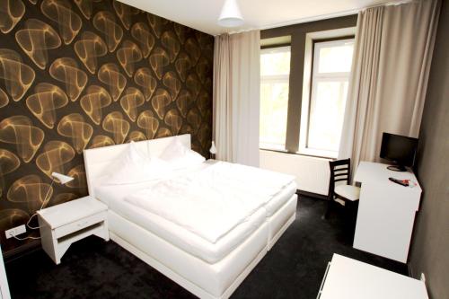 a bedroom with a white bed with a wall at Hostaria da Marcello - in Markkleeberg