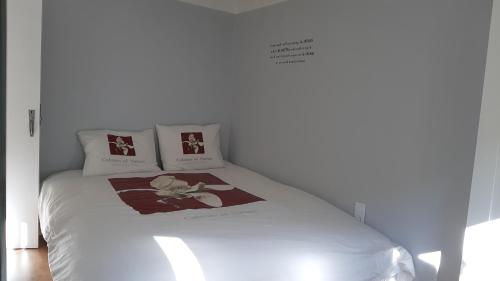 Una cama blanca con 2 almohadas y un cartel. en Trevim, en Lousã