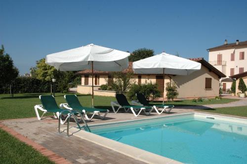 a group of chairs and umbrellas next to a pool at Il Podere del Falco in Assisi