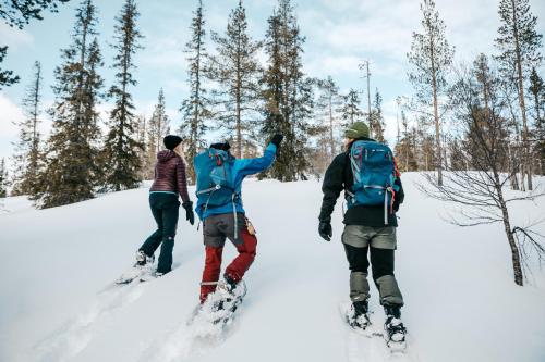 a group of three people standing in the snow at Lapland Hotels Ounasvaara Chalets in Rovaniemi