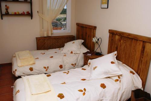 um quarto com 2 camas com lençóis brancos e almofadas em Casa Monica em Narrillos de San Leonardo