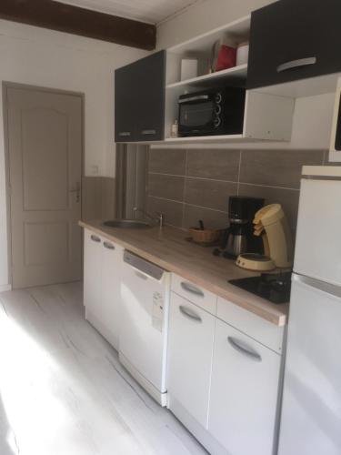 a kitchen with white cabinets and a white refrigerator at Appartements La Durance et L'Helpe in Embrun
