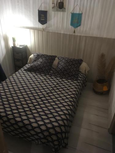 a bedroom with a bed with a black and white comforter at Appartements La Durance et L'Helpe in Embrun