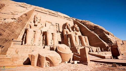 an ancient building with statues on the side of a cliff at Safari Abu Simbel in Abu Simbel
