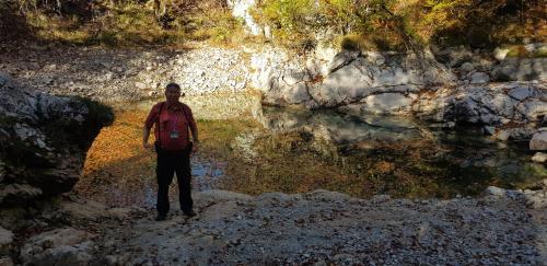 a man with a backpack standing in front of a pool of water at PROKLETIJE eko katun Vusanje in Gusinje