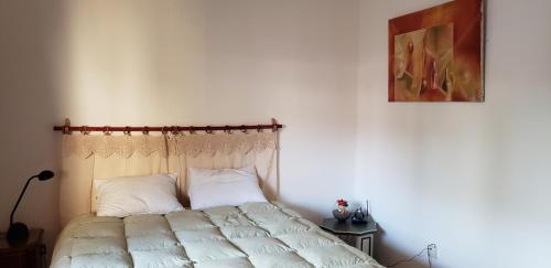 1 dormitorio con 1 cama con sábanas blancas y una pintura en La casa del Paseo en Salta