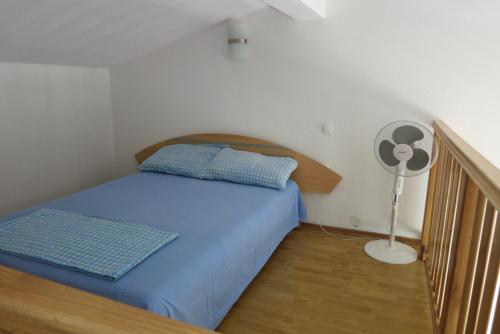 a small bedroom with a bed and a fan at Apartments Pehar in Zaostrog