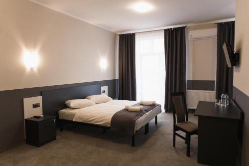 a bedroom with a bed and a desk and a chair at GOLDEN RING in Ternopilʼ