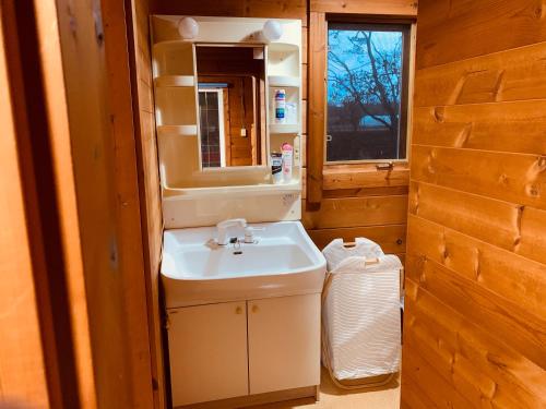 un baño con lavabo y espejo en Tomy's Log House - Need CAR, en Shiraoi