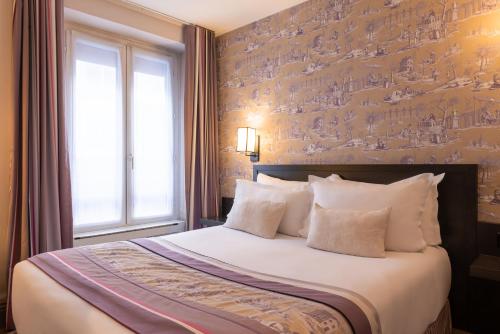a bedroom with a large bed with white pillows at Hôtel France d'Antin Opéra in Paris