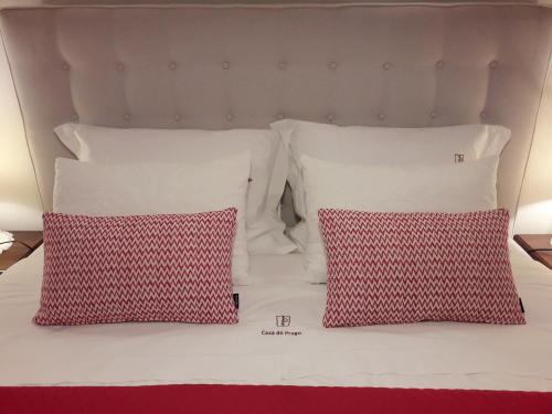 Una cama con dos almohadas rojas y blancas. en Casa do Progo, en Ponte de Lima