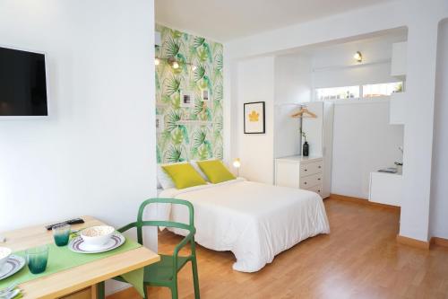 a white bedroom with a bed and a table with a tableablish at Alemania & SOHO by ELE Apartments in Málaga