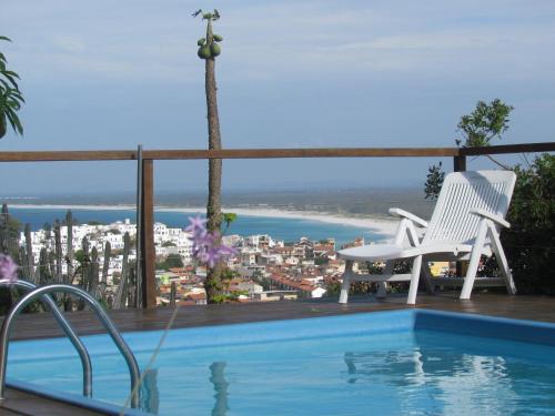 a swimming pool with two chairs and a view of the ocean at Casa Pontal do Atalaia in Arraial do Cabo