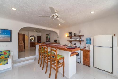 a kitchen with a bar with stools and a refrigerator at Del Sol Beachfront in Akumal