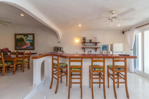 a kitchen with a bar with chairs and a table at Del Sol Beachfront in Akumal