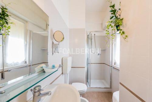 La salle de bains blanche est pourvue d'un lavabo et d'un miroir. dans l'établissement Hotel Alda, à Cervia