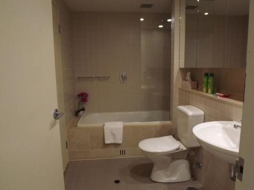 a bathroom with a toilet and a tub and a sink at Beachside Luxury Apartments One & Two Bedroom in Beachfront Oaks Pier Building in Glenelg