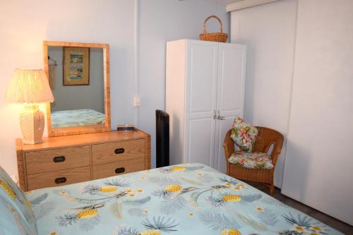 a bedroom with a bed and a dresser and a mirror at Maui Vista 1313 in Kihei