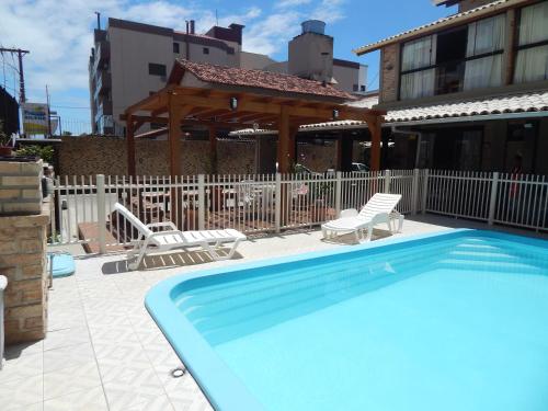 uma piscina com duas cadeiras e um gazebo em Pousada Salines em Florianópolis