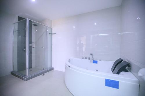 a white bathroom with a shower and a tub at La Maja Rica Hotel in Tarlac
