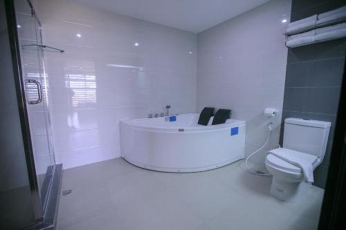 a white bathroom with a tub and a toilet at La Maja Rica Hotel in Tarlac