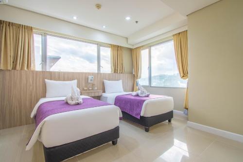 two beds in a hotel room with windows at Alicia Apartelle in Cebu City