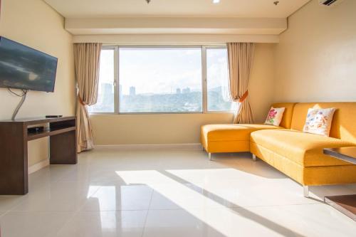 a living room with a yellow couch and a large window at Alicia Apartelle in Cebu City