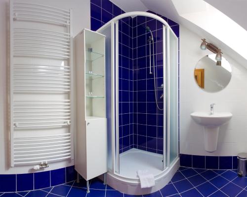 a blue tiled bathroom with a shower and a sink at Havířská bouda in Kutná Hora