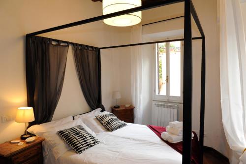 1 dormitorio con cama negra con dosel y ventana en Suite Lungara, en Roma