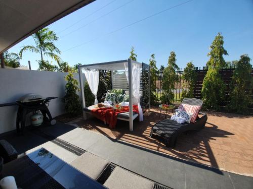 a patio with a gazebo and a bed and a chair at 4 BDR Gardens Escape Inner City Townhouse with Secure Parking and Spa in Darwin