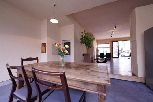 a dining room table with chairs and a vase of flowers at Guest House Kadoyasu in Kanazawa