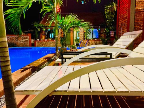 a row of white benches next to a swimming pool at Vu's Homestay in Phong Nha