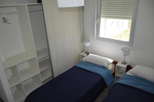 - une petite chambre avec 2 lits et une fenêtre dans l'établissement Villa Bono, à Santa Clara del Mar
