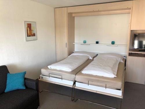a bedroom with two beds and a couch and a tv at Studio Ravaisch in Davos