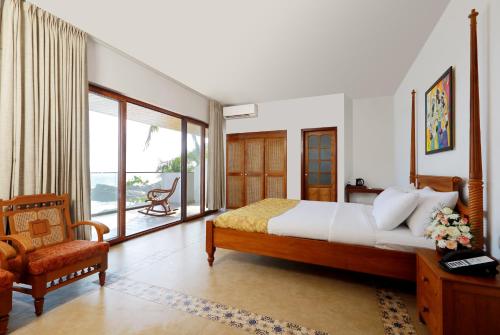 a bedroom with a bed and a chair and a window at Rockholm at the Light House Beach in Kovalam