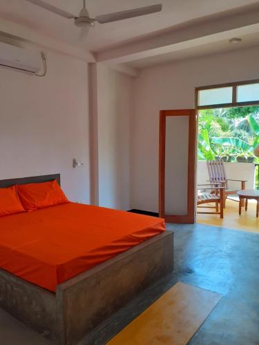 a bedroom with a bed with an orange comforter at Om Villa in Hikkaduwa