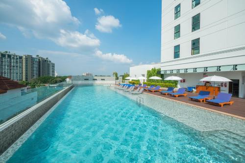 una piscina con sillas azules y un edificio en The Empress Premier Chiang Mai - SHA Extra Plus en Chiang Mai