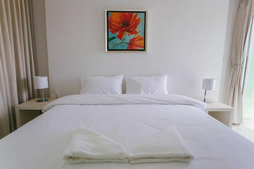a white bed in a bedroom with two lamps at The Terrace Hotel in Nakhon Si Thammarat