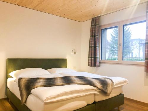 a bedroom with a bed with a green headboard and a window at Woodpecker Chalets in Klösterle am Arlberg