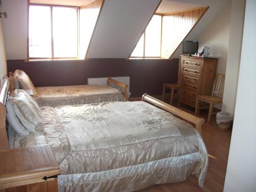 a bedroom with two beds and a dresser and two windows at Clare Street B&B in Nenagh