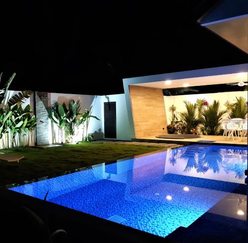 a house with a swimming pool at night at Villa KHAO MANEE in Ban Sakhu