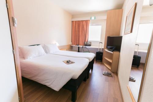 a hotel room with a large bed and a television at Ibis Jerez De La Frontera Cadiz in Jerez de la Frontera