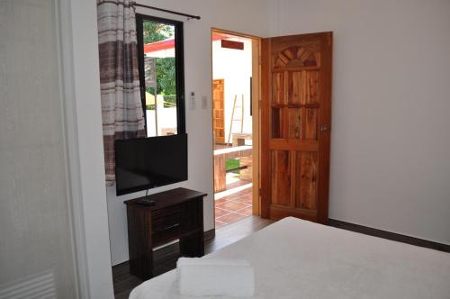 ein Wohnzimmer mit einem TV und einer Tür in der Unterkunft CASA MIA INN in Dauis