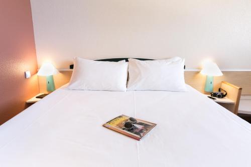 a book sitting on top of a white bed at Ibis Jerez De La Frontera Cadiz in Jerez de la Frontera