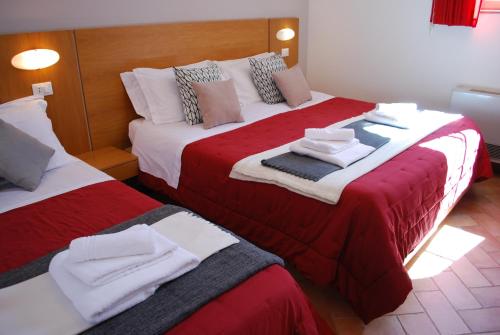 a hotel room with two beds with red and white sheets at Residence Gli Ulivi in Castel di Lama