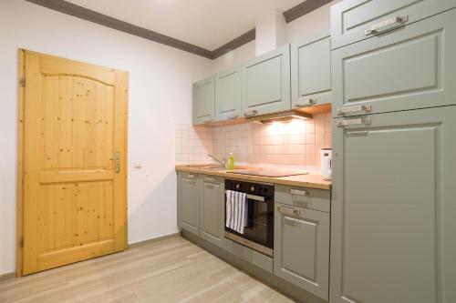 kuchnia z szarymi szafkami i drewnianymi drzwiami w obiekcie Wohnung Waldkauz im Haus Seeadler w Zinnowitz